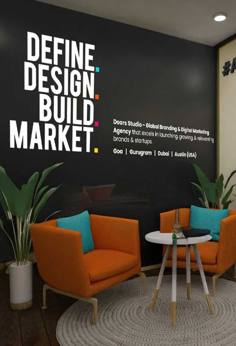 Studio lounge with orange chairs beneath a “Define. Design. Build. Market.” wall